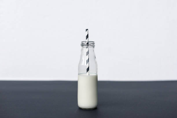 istock glass bottle with milk and striped drinking straw on grey 907972242