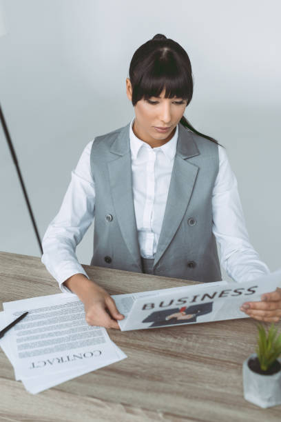 istock businesswoman reading newspaper isolated on gray 907972578