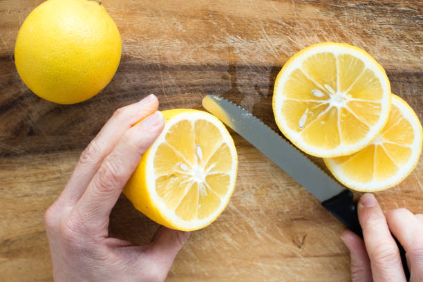 istock Cropped Image Of Hand Cutting Lemon On Cutting Board 907974284