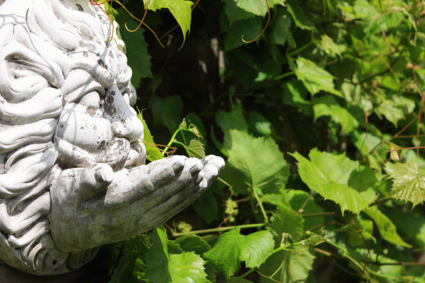 Concrete grey garden decor hanging face blowing tree wind spirit in front of green wine grape leaves