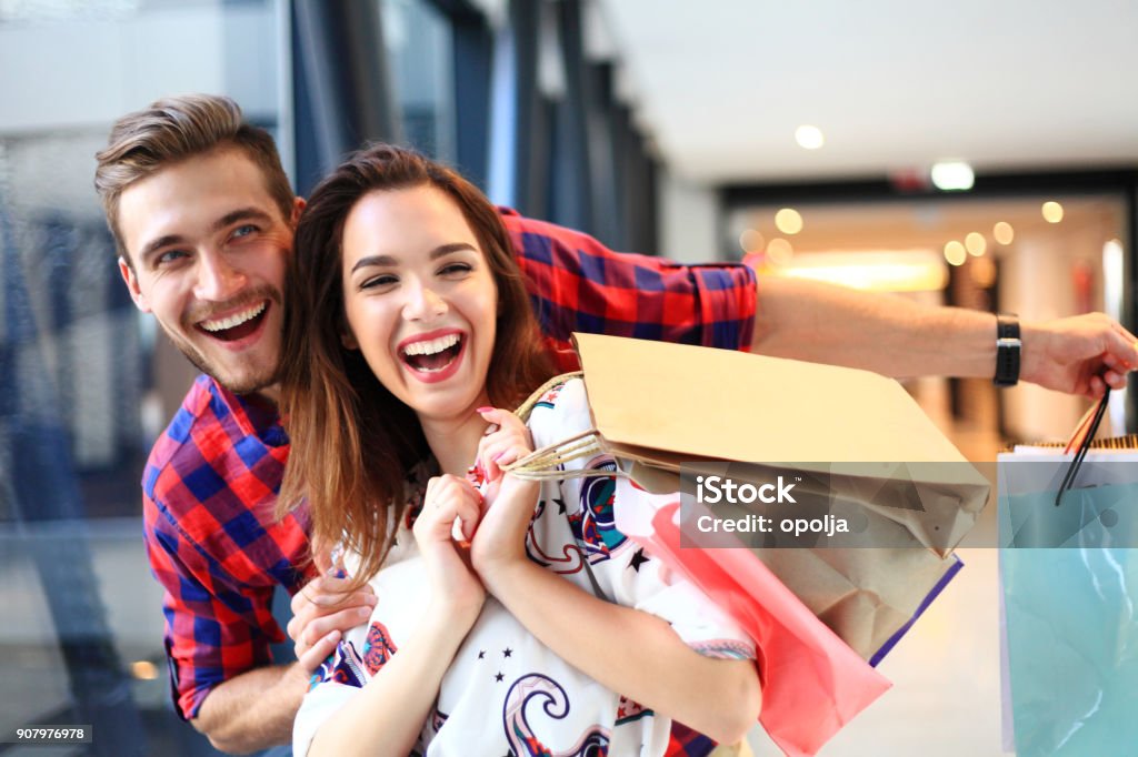 vente, consumérisme et gens concept - heureux jeune couple avec sacs à provisions à pied au centre commercial. - Photo de Commerce libre de droits