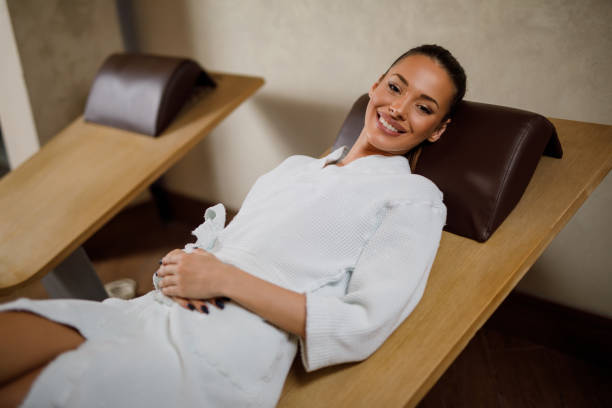 istock Woman in bathrobe relaxing in lounge chairs at spa 907977452