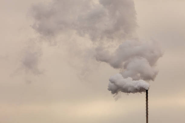 istock Smoke from chimney on dark cloudy sky 907978326