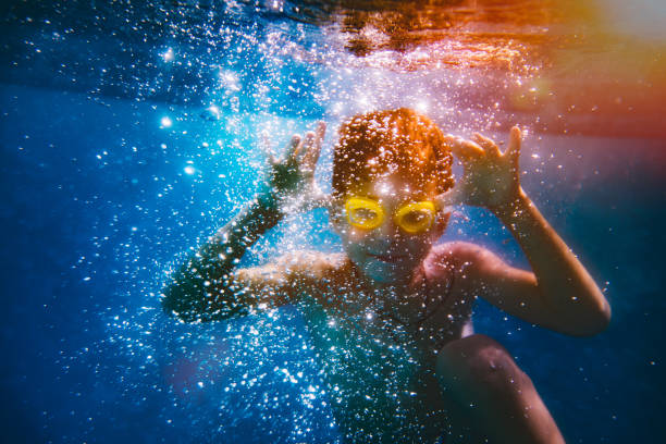 istock Young boy having fun swimming underwater on summer holidays 907983998