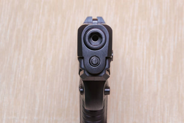 istock Black gun isolated on light coloured background 907989564