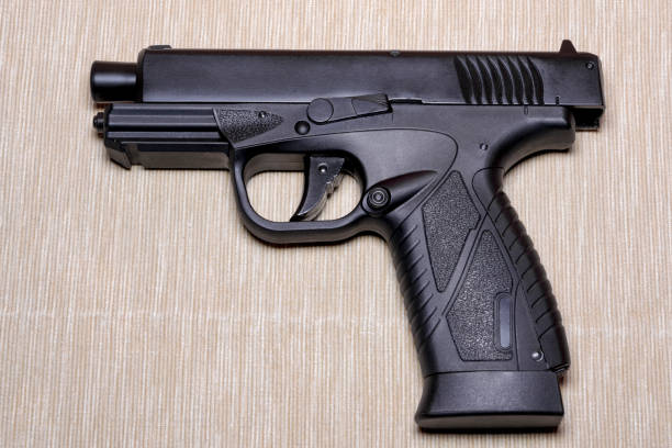 istock Black gun isolated on light coloured background 907990036
