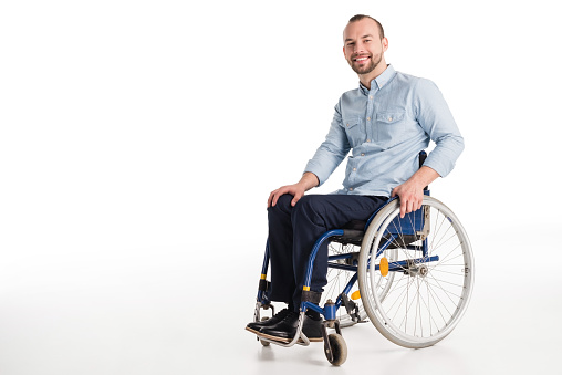 smiling disabled man in wheelchair looking at camera, isolated on white