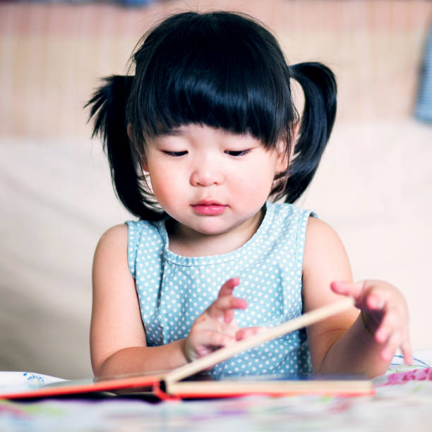istock Charming and lovely asian kid reading book 907992312