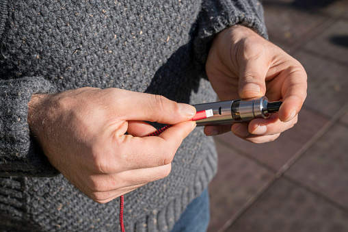 A man charging an electronic cigarette in the park