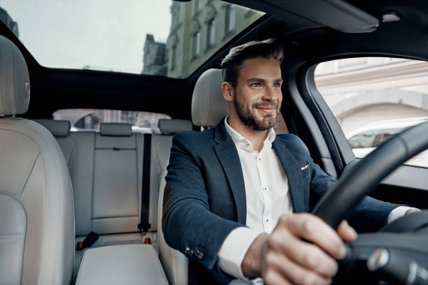 Success in motion. Handsome young man in full suit smiling while driving a car car interior stock pictures, royalty-free photos & images