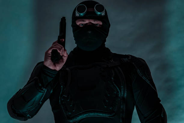 istock Armed spy in bulletproof vest. The gun is raised. 907998370