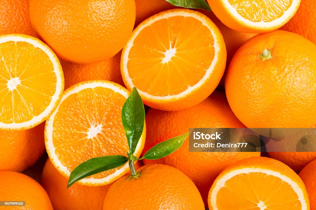 Picked orange fruits. Fresh orange fruits with green leaves as background. Orange - Fruit Stock Photo