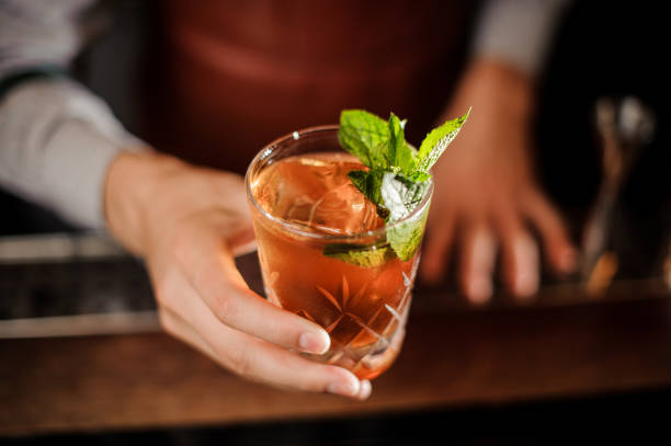 istock Bartender is holding a shot glass with alcoholic drink and mint 908001626