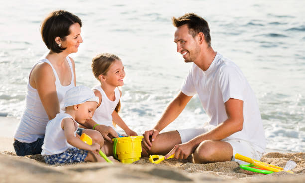 istock Parents with two kids playing with toys on beach 908001718