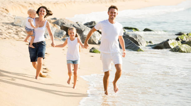 istock parents with two kids jogging on beach 908001830