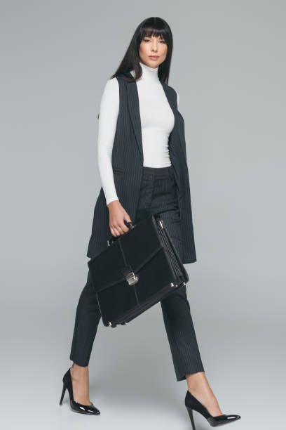 istock attractive brunette businesswoman walking with briefcase on gray 908004496