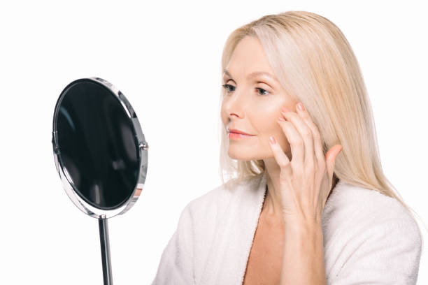 istock mature woman looking at mirror 908004838