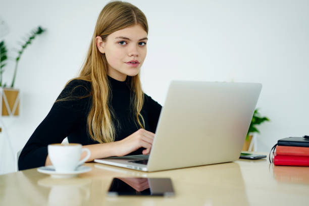 half length portrait of beautiful female manager sitting at laptop device connecting to wireless internet and working in office interior.attractive copywriter with modern computer looking at camera - working at home administrator computer university imagens e fotografias de stock