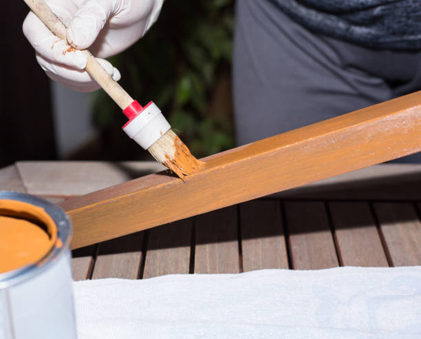 istock Woman strokes a wooden table with fresh paint 908013614