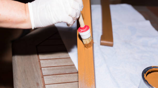istock Woman strokes a wooden table with fresh paint 908013804