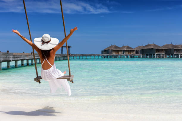 Happy female traveller on a swing at a tropical beach