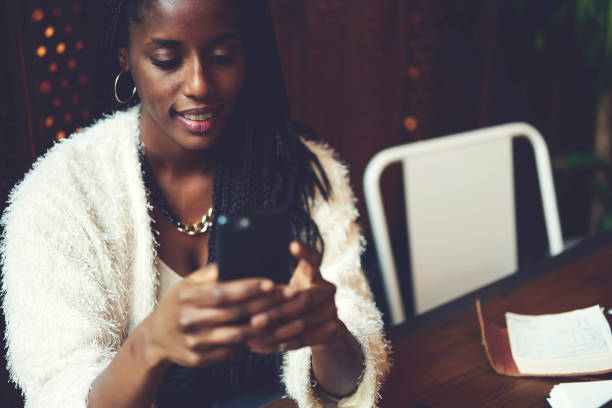 istock Attractive good looking afro american female downloading innovative application via mobile phone, charming teen girl playing online games during leisure using free wireless connection to internet 908017890