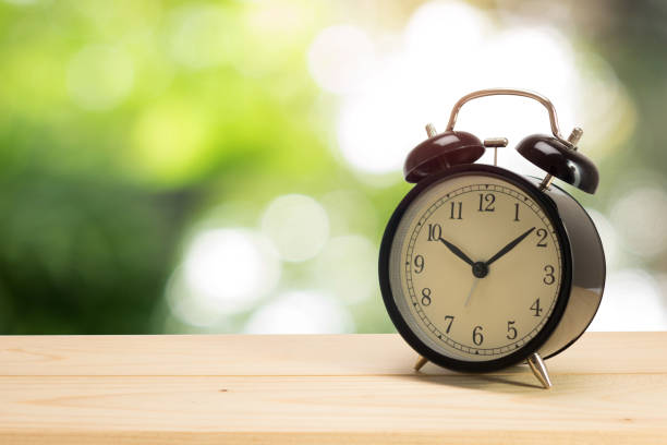 istock Retro alarm clock on table with green background 908019570
