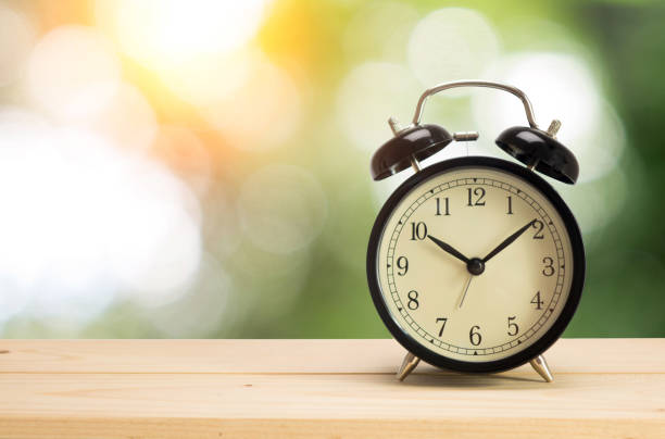 istock Retro alarm clock on table with green background 908019592