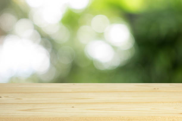 istock wood shelf on blurred green leaves background 908020242