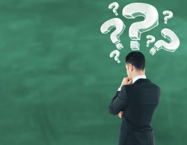 istock businessman on chalkboard background looking at drawn question marks 908025182