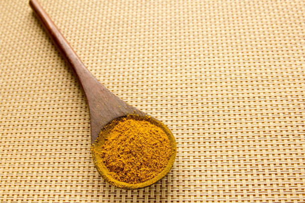 Powder curry in a wooden spoon on the table. Close-up.