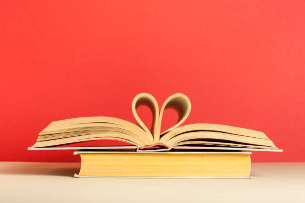 istock Book pages folded in heart shape on red background. Copy space for text. 908034244