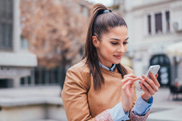 istock Charming young woman using smartphone outdoors. Close-up. 908034356