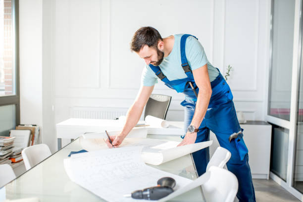 istock Repairman with paper drawings at the office 908034752