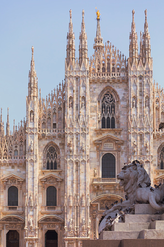 A lion sculpture from the monument to Vittorio Emanuele II on Piazza del Duomo in Milan - behind it the 'Duomo', Milan Cathedral.