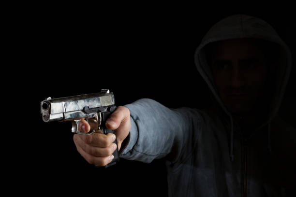 Adult Gunman Aiming Handgun In Dark stock photo