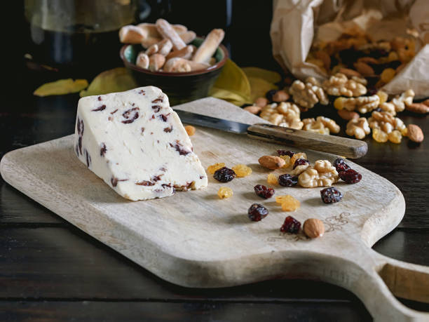 molkerei käse mit preiselbeeren, nüssen und rosinen auf holzbrett. - english walnut stock-fotos und bilder