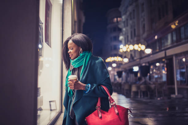 Young woman, African - American ethnicity, looking at the shop window. It's Christmas time Young woman, African - American ethnicity, looking at the shop window. It's Christmas time window shopping stock pictures, royalty-free photos & images