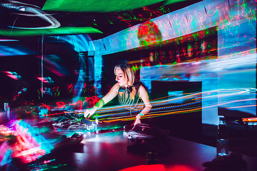 Joven mujer DJ mezclando música en una discoteca photo