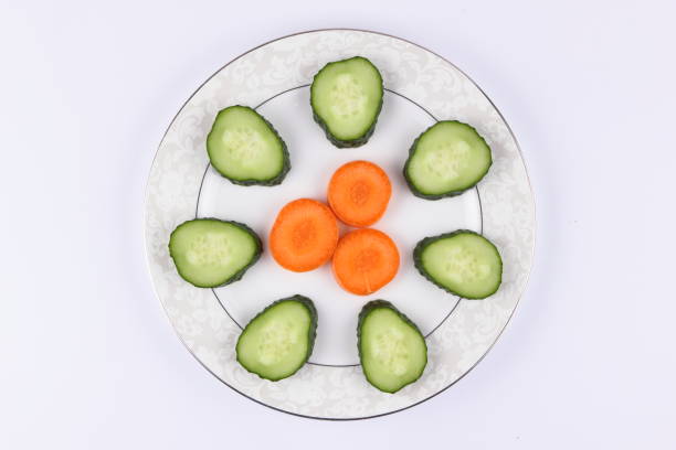 Sliced cucumbers and carrots on a plate, fresh vegetables, minimalism, empty space, top view, cucumbers and carrots on white background, healthy food, diet, packaging design