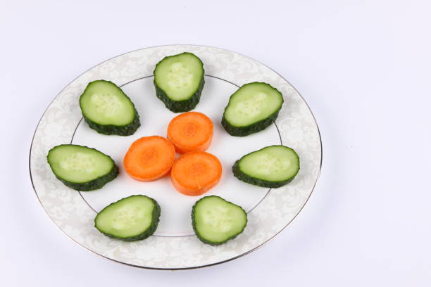 Sliced cucumbers and carrots on a plate, fresh vegetables, minimalism, empty space, top view, cucumbers and carrots on white background, healthy food, diet, packaging design