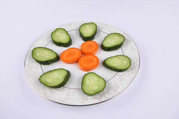 Sliced cucumbers and carrots on a plate, fresh vegetables, minimalism, empty space, top view, cucumbers and carrots on white background, healthy food, diet, packaging design
