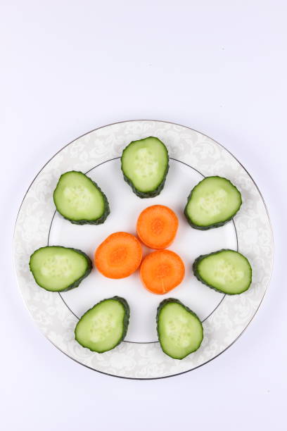 Sliced cucumbers and carrots on a plate, fresh vegetables, minimalism, empty space, top view, cucumbers and carrots on white background, healthy food, diet, packaging design