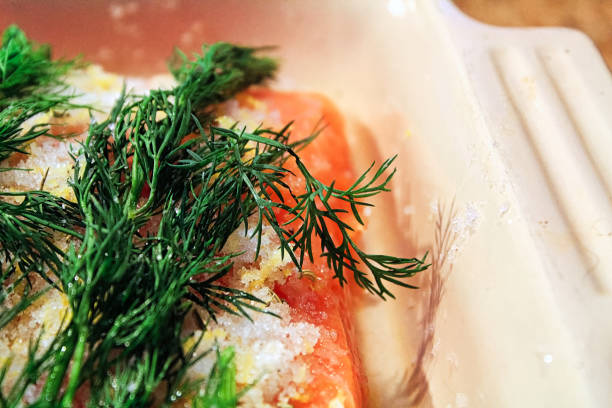 Thinly sliced smoked salmon garnished with lemon slices and rosemary, elegantly presented on parchment paper for serving.