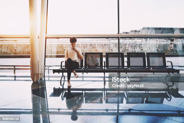 Black Girl Using Cellphone In Waiting Hall Of Airport Stock Photo - Download Image Now