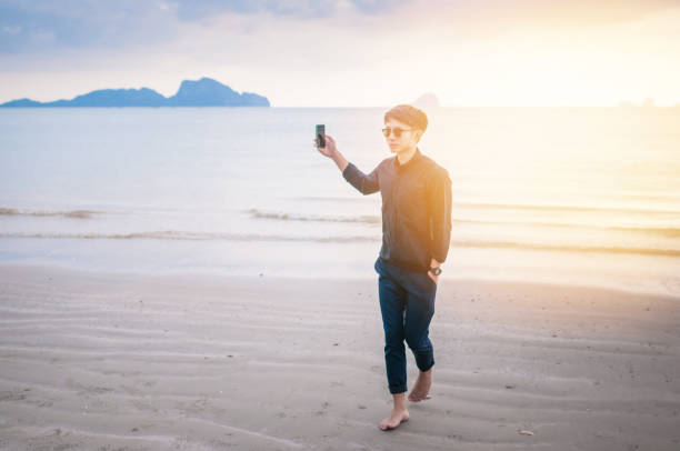 istock Relaxing Businessman using  laptop and smartphone on the beach 908126594