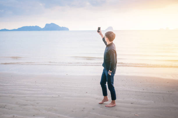 istock Relaxing Businessman using  laptop and smartphone on the beach 908126626