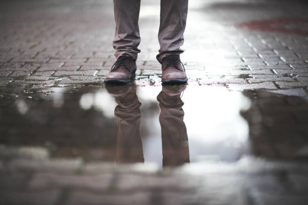 Puddle of rain with standing people