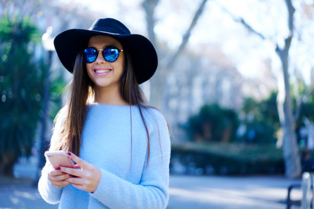 istock Cheerful attractive tourist in cool hat enjoying recreation while messaging with friends using application on telephone connected to 4G.Young smiling hipster girl blogging while walking outdoors 908131194