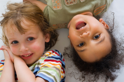 A young blond boy and a beautiful mixed race little girl laughing for the camera